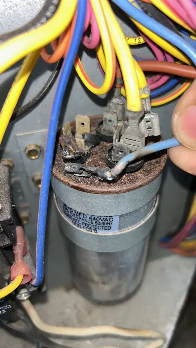 Old burnt capacitor removed during AC repair