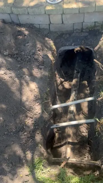 Excavated trench showing a sagging belly in an old sewer line beside a home in Neptune Beach, FL